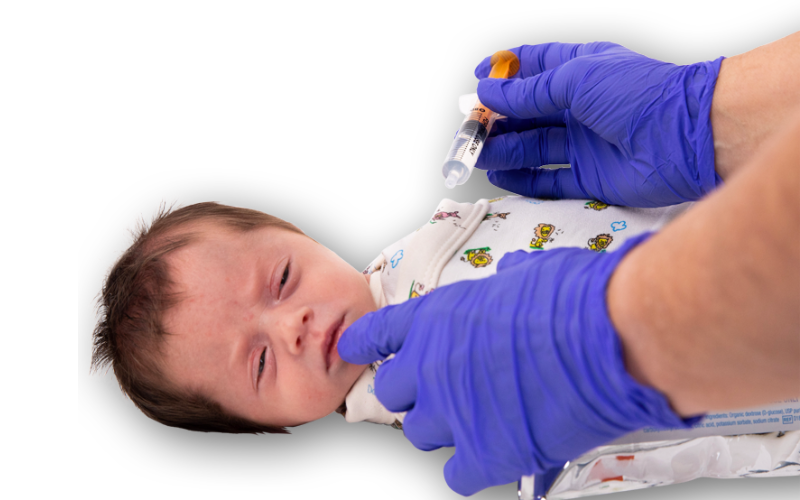 Gloved clinician administering Sweet Cheeks glucose gel to baby.