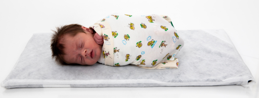 Baby in the Dandle® ROO2 positioning aid, laying on the Tranquilo® Soothing Mat.